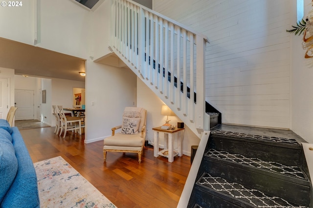 stairway featuring wood-type flooring and a high ceiling