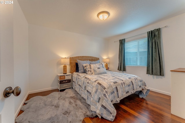 bedroom featuring a textured ceiling and dark hardwood / wood-style flooring