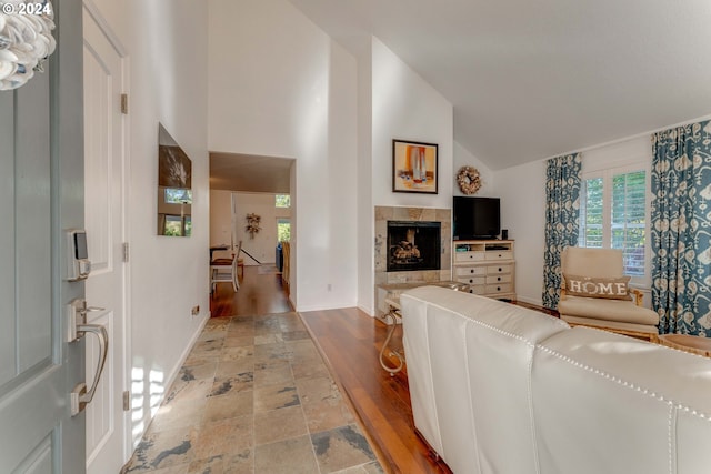 living room featuring high vaulted ceiling, wood-type flooring, and a fireplace