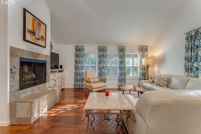 living room featuring a tile fireplace, lofted ceiling, and dark hardwood / wood-style floors