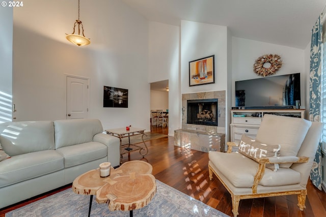 living room featuring a tiled fireplace, hardwood / wood-style floors, and high vaulted ceiling