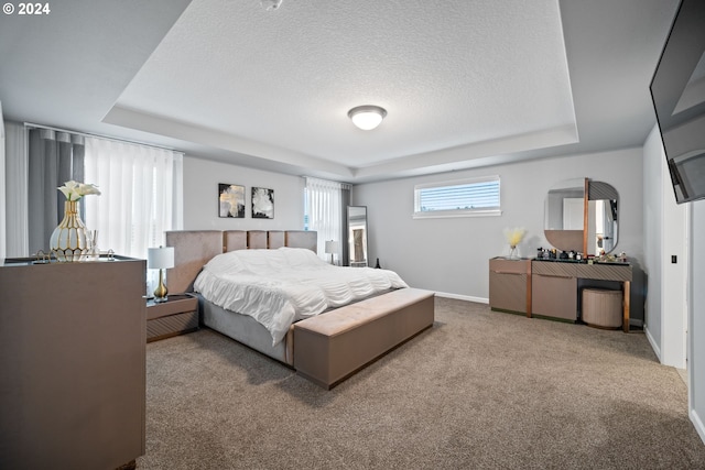 carpeted bedroom with a textured ceiling and a tray ceiling