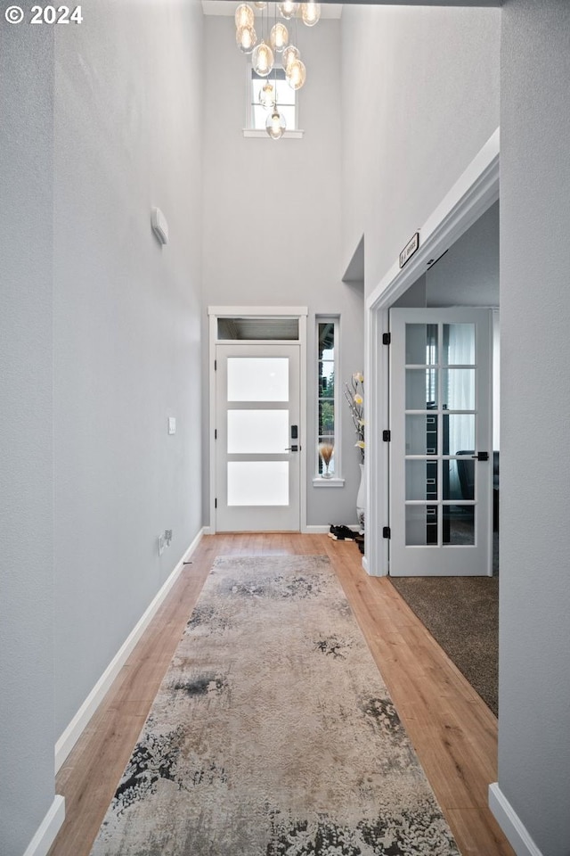 entryway featuring an inviting chandelier, light wood-type flooring, and a high ceiling