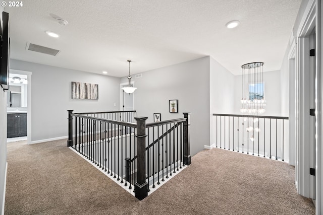 hallway featuring carpet floors, a textured ceiling, and a chandelier