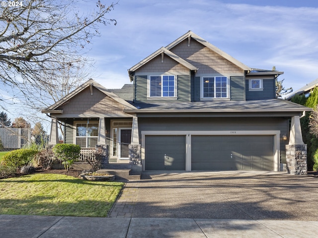 craftsman house with covered porch, a garage, and a front lawn