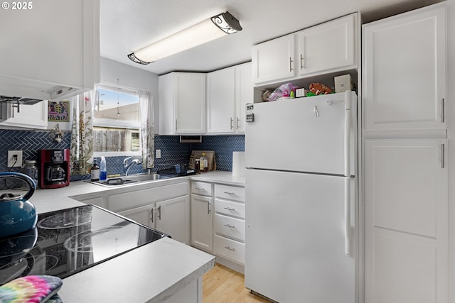 kitchen with decorative backsplash, white refrigerator, white cabinetry, and sink