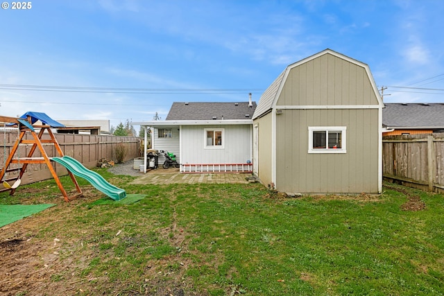 rear view of property featuring a storage unit, a playground, and a yard