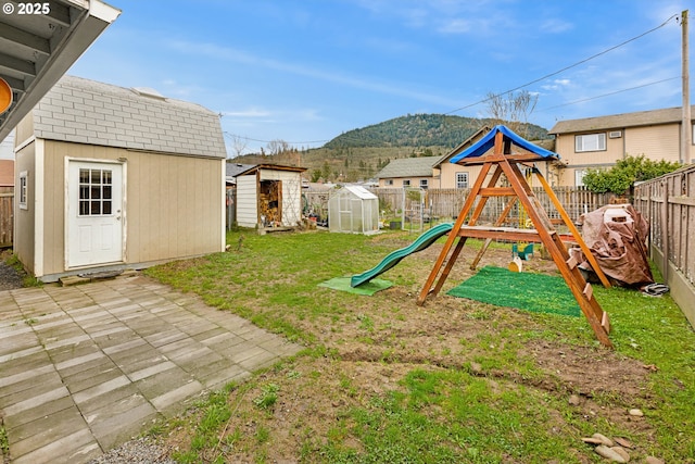 view of playground featuring a lawn, a storage unit, a patio area, and a mountain view