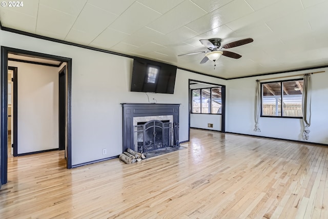 unfurnished living room featuring ceiling fan, ornamental molding, and light wood-type flooring