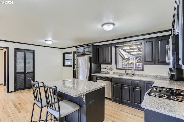 kitchen featuring sink, light stone counters, a center island, light hardwood / wood-style flooring, and appliances with stainless steel finishes