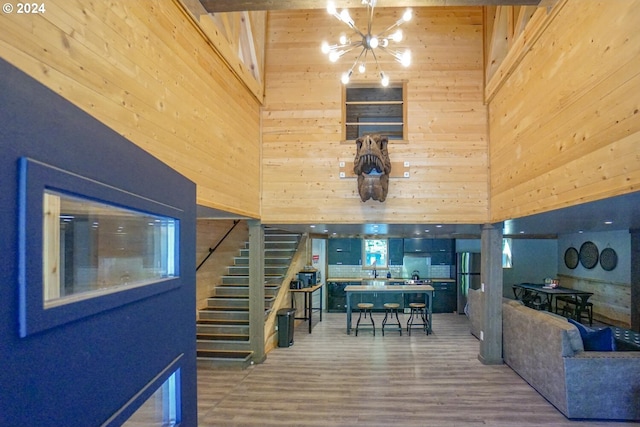 interior space with a chandelier, hardwood / wood-style floors, a towering ceiling, and wood walls