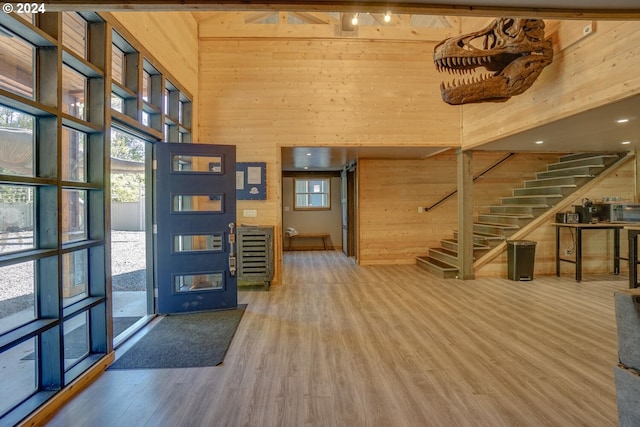 foyer with hardwood / wood-style floors, a towering ceiling, and wood walls