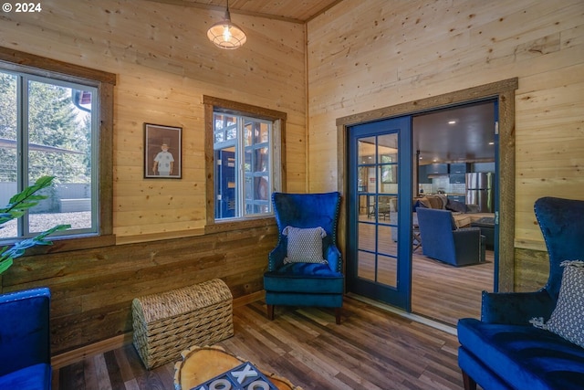 sitting room featuring wood-type flooring, wooden walls, and vaulted ceiling