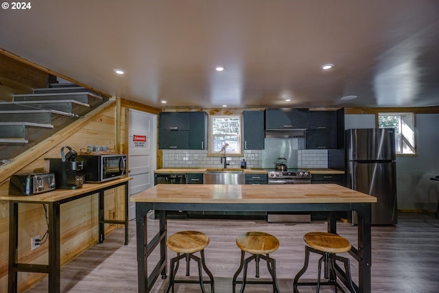 kitchen with butcher block counters, sink, dark hardwood / wood-style floors, a kitchen bar, and appliances with stainless steel finishes