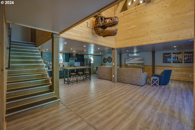 living room with a towering ceiling, hardwood / wood-style flooring, and wood walls