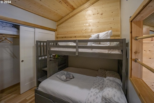 bedroom featuring light hardwood / wood-style flooring, wood walls, vaulted ceiling, a closet, and wood ceiling