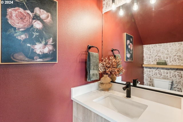 bathroom featuring vanity, toilet, and vaulted ceiling