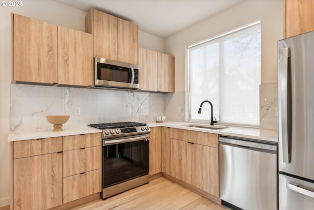 kitchen featuring light brown cabinetry, sink, stainless steel appliances, and light hardwood / wood-style flooring