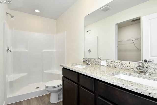 bathroom featuring hardwood / wood-style flooring, vanity, toilet, and walk in shower