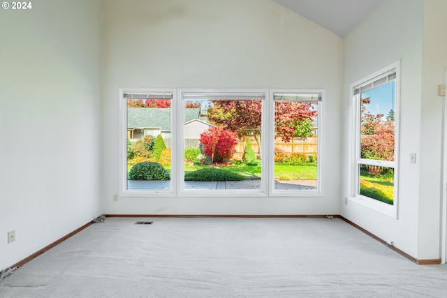 carpeted empty room with high vaulted ceiling and a wealth of natural light