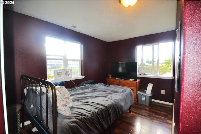 bedroom featuring multiple windows and dark hardwood / wood-style flooring