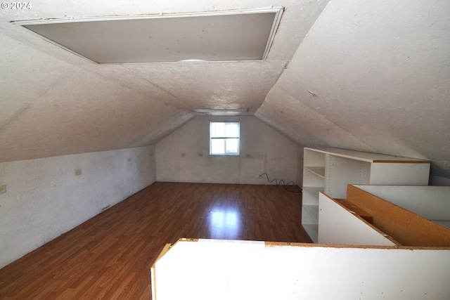 additional living space featuring dark wood-type flooring and vaulted ceiling