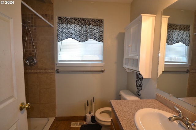 bathroom featuring vanity, a tile shower, and toilet