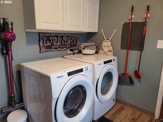 laundry room featuring cabinets, wood-type flooring, washing machine and dryer, and electric panel