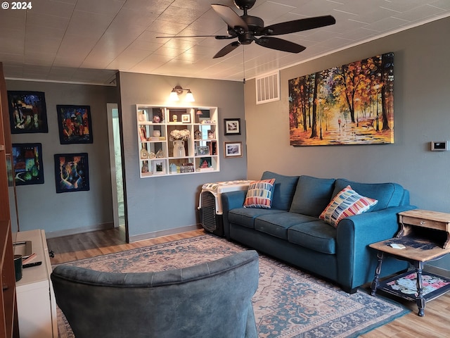 living room featuring hardwood / wood-style floors, ceiling fan, and ornamental molding