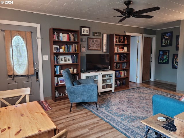 living room featuring ceiling fan, wood-type flooring, and crown molding