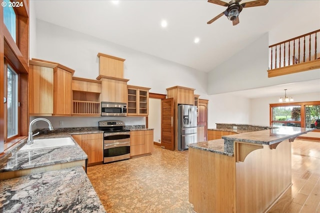 kitchen with sink, a center island, high vaulted ceiling, dark stone countertops, and appliances with stainless steel finishes