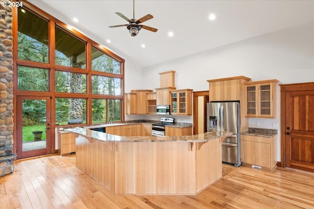 kitchen featuring a breakfast bar area, appliances with stainless steel finishes, high vaulted ceiling, light stone counters, and light hardwood / wood-style floors