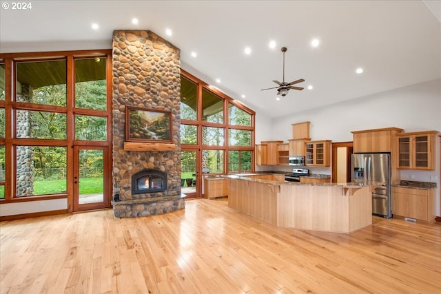 kitchen with appliances with stainless steel finishes, high vaulted ceiling, a kitchen bar, plenty of natural light, and a spacious island