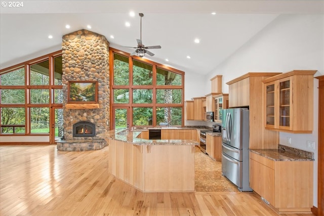 kitchen featuring light hardwood / wood-style flooring, stone counters, appliances with stainless steel finishes, plenty of natural light, and high vaulted ceiling