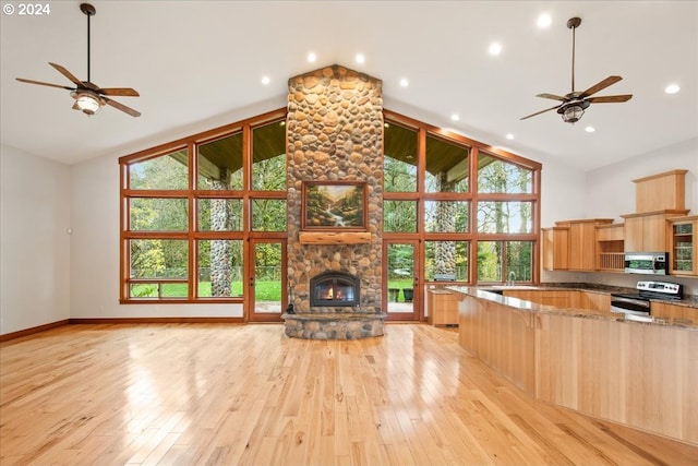 living room featuring ceiling fan, a fireplace, light wood-type flooring, and a wealth of natural light