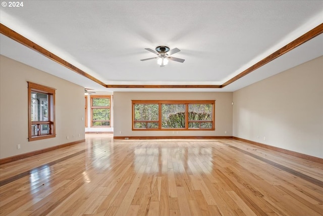 unfurnished living room with ceiling fan, a wealth of natural light, and light wood-type flooring