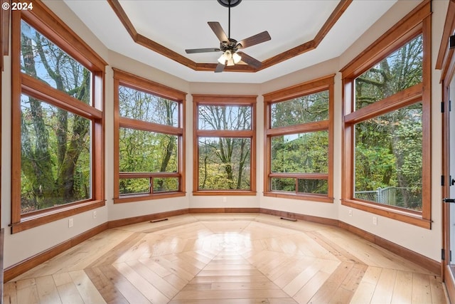 unfurnished sunroom with ceiling fan, plenty of natural light, and a raised ceiling