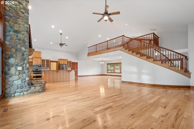 unfurnished living room featuring ceiling fan, light hardwood / wood-style floors, and high vaulted ceiling