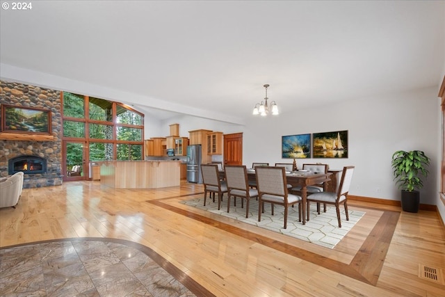 dining space featuring an inviting chandelier, a fireplace, light hardwood / wood-style floors, and vaulted ceiling