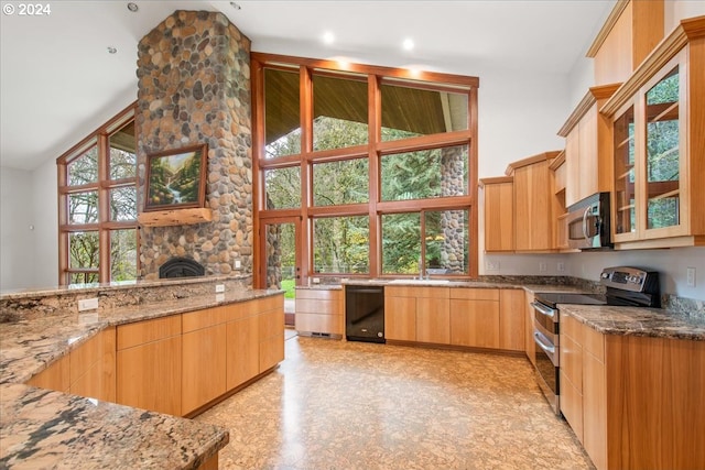 kitchen with stainless steel appliances, light stone countertops, light brown cabinets, and a wealth of natural light