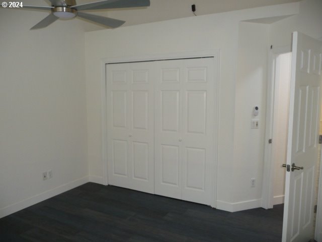 unfurnished bedroom with ceiling fan, a closet, and dark hardwood / wood-style floors