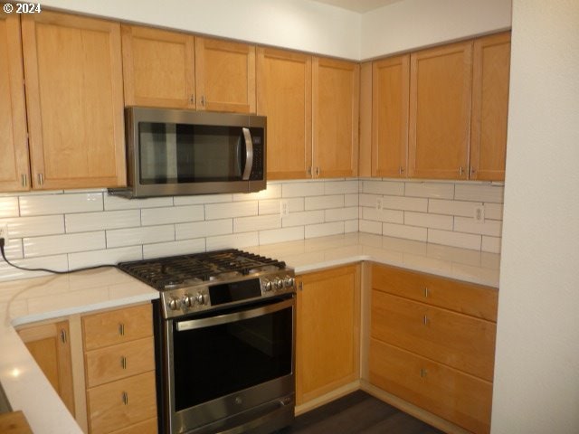 kitchen featuring decorative backsplash, dark hardwood / wood-style flooring, and appliances with stainless steel finishes