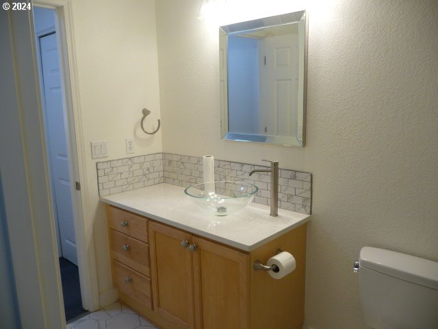 bathroom with backsplash, tile patterned floors, vanity, and toilet