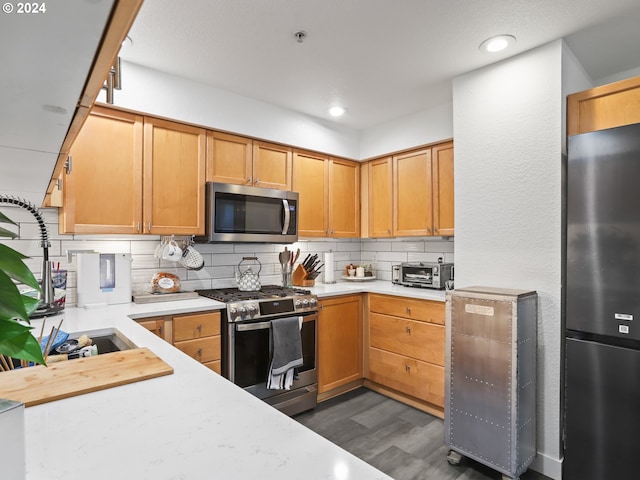 kitchen with appliances with stainless steel finishes, backsplash, dark hardwood / wood-style floors, and sink