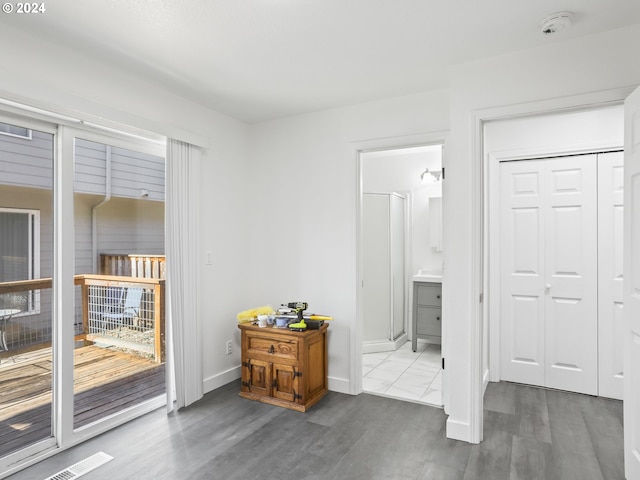 interior space featuring access to outside, connected bathroom, a closet, and hardwood / wood-style flooring