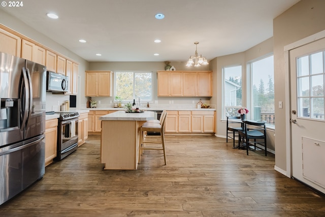 kitchen with pendant lighting, dark wood-type flooring, a breakfast bar area, a kitchen island, and stainless steel appliances