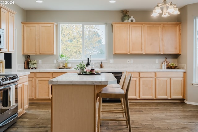 kitchen featuring pendant lighting, tile countertops, light hardwood / wood-style floors, light brown cabinetry, and a kitchen island