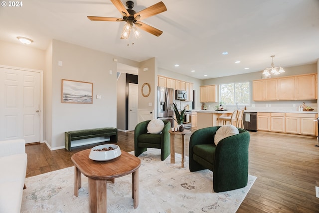 living room with ceiling fan with notable chandelier and light wood-type flooring