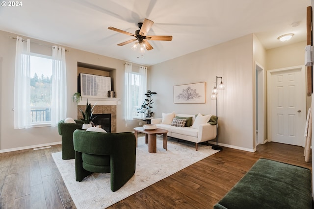 living room featuring a tiled fireplace, ceiling fan, and wood-type flooring