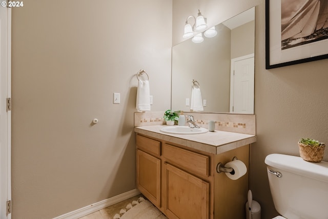 bathroom featuring toilet, vanity, tile patterned floors, and backsplash